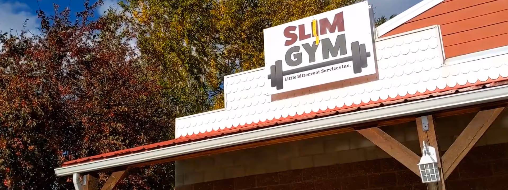 Exterior view of the facility with a Slim Gym sign and Little Bitterroot Services.