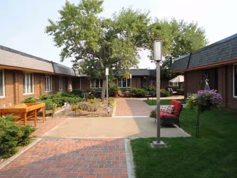 A brick courtyard with walkways, greenery, and outdoor seating surrounded by single-story brick buildings.