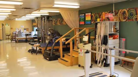 Indoor rehab gym at The Manor of Kenosha with treadmills, parallel bars, and therapy rails.