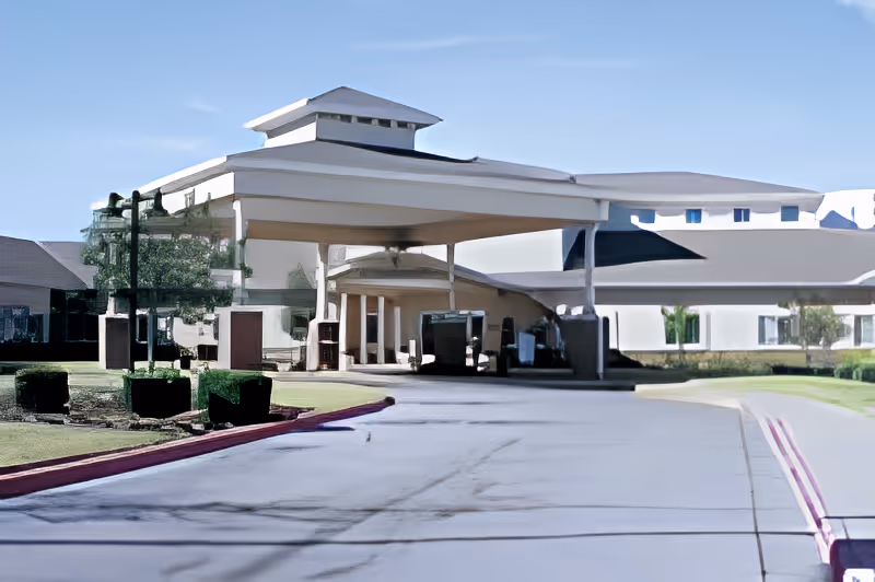 Front entrance with a covered porte-cochere and driveway at the Brookdale Overland Park building, with landscaped grounds.
