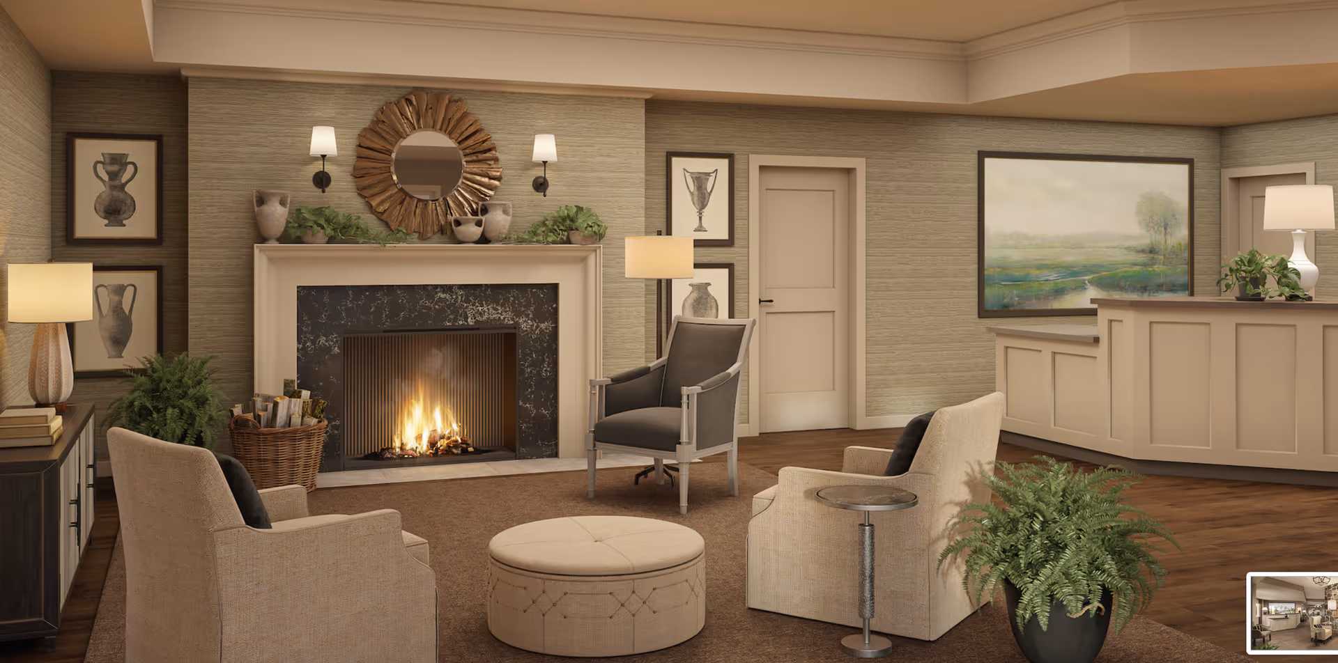 A cozy senior living facility common area with a lit fireplace surrounded by a beige mantel and black marble. The room features three armchairs around a round beige ottoman, a side table, and several lamps providing warm lighting. The walls are decorated with framed artwork and a round decorative mirror above the fireplace. There are green plants placed around the room, and a reception desk is visible in the background with a large landscape painting on the wall behind it.