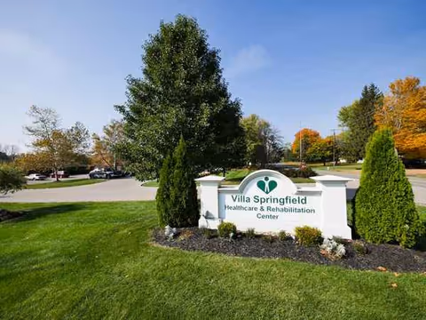 Entrance sign for Villa Springfield Healthcare & Rehabilitation Center with trees and a parking lot.