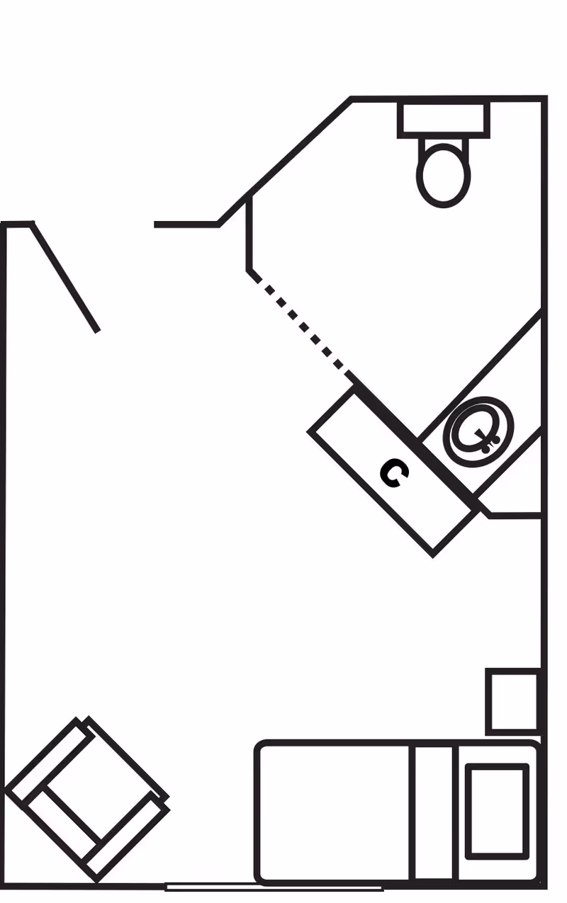 Black-and-white floor plan of a small studio room showing a bed, armchair, and an angled bathroom with a toilet and sink/vanity.