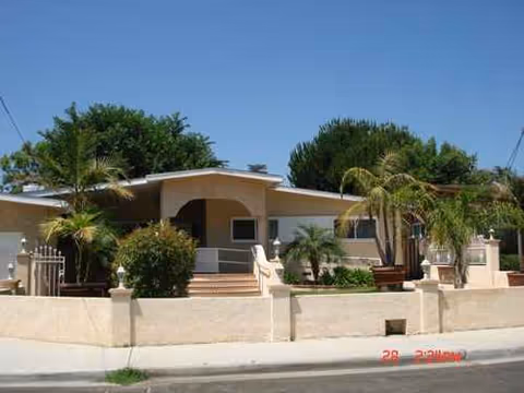 Front view of Peppertree Guest Home II, single-story beige senior living home with a gated yard.
