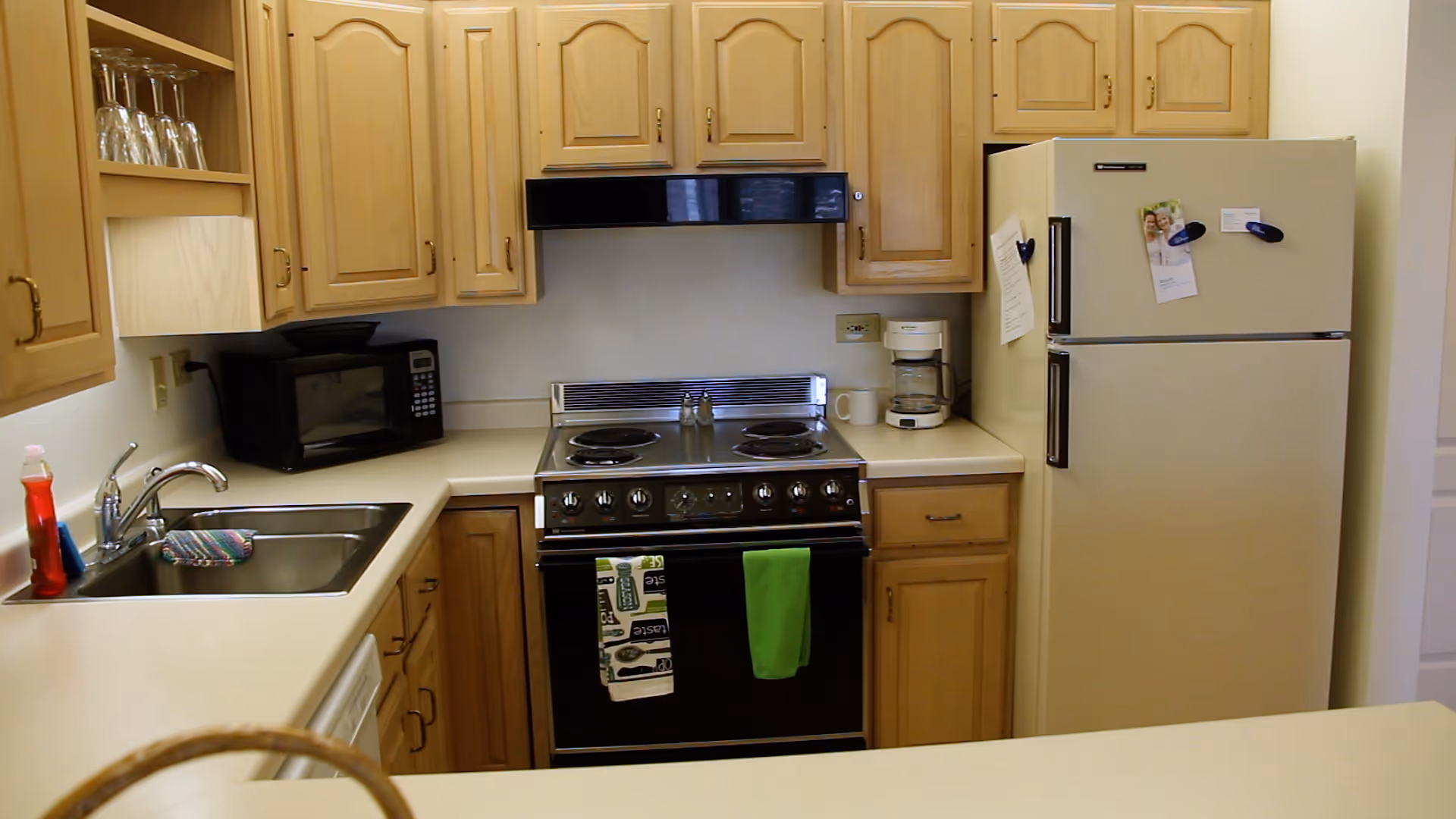 Assisted living kitchen with wood cabinets, stove, fridge, microwave, and sink.
