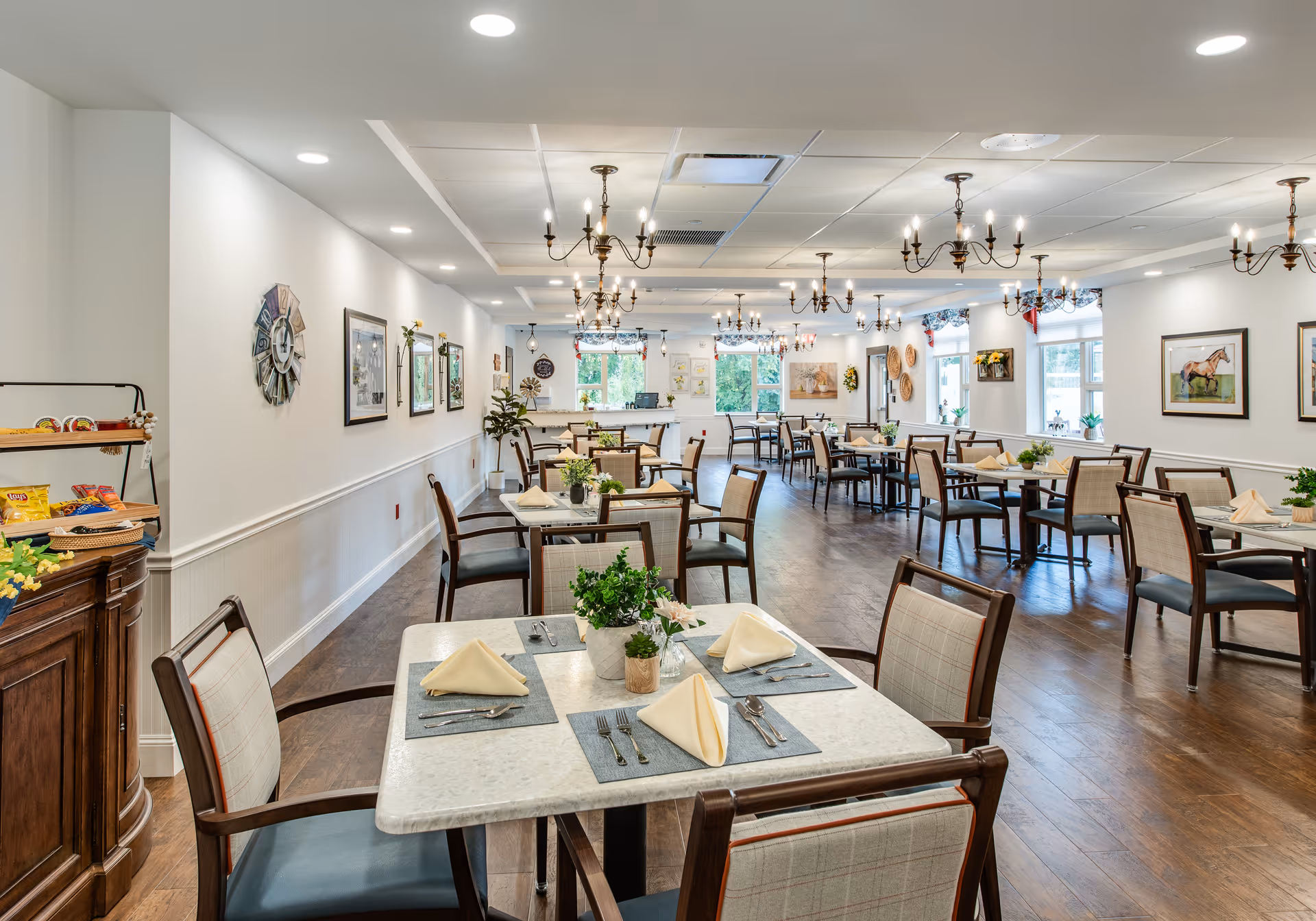 Spacious, well-lit dining room with multiple set tables, chandeliers, and large windows.