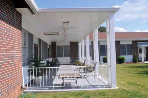 Covered outdoor walkway at Eastview Rehabilitation & Healthcare Center with bench and white railing.