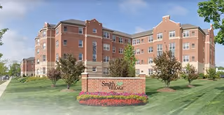 Brick multi-story senior living building set behind a lawn with a brick sign that reads "Smith Village".