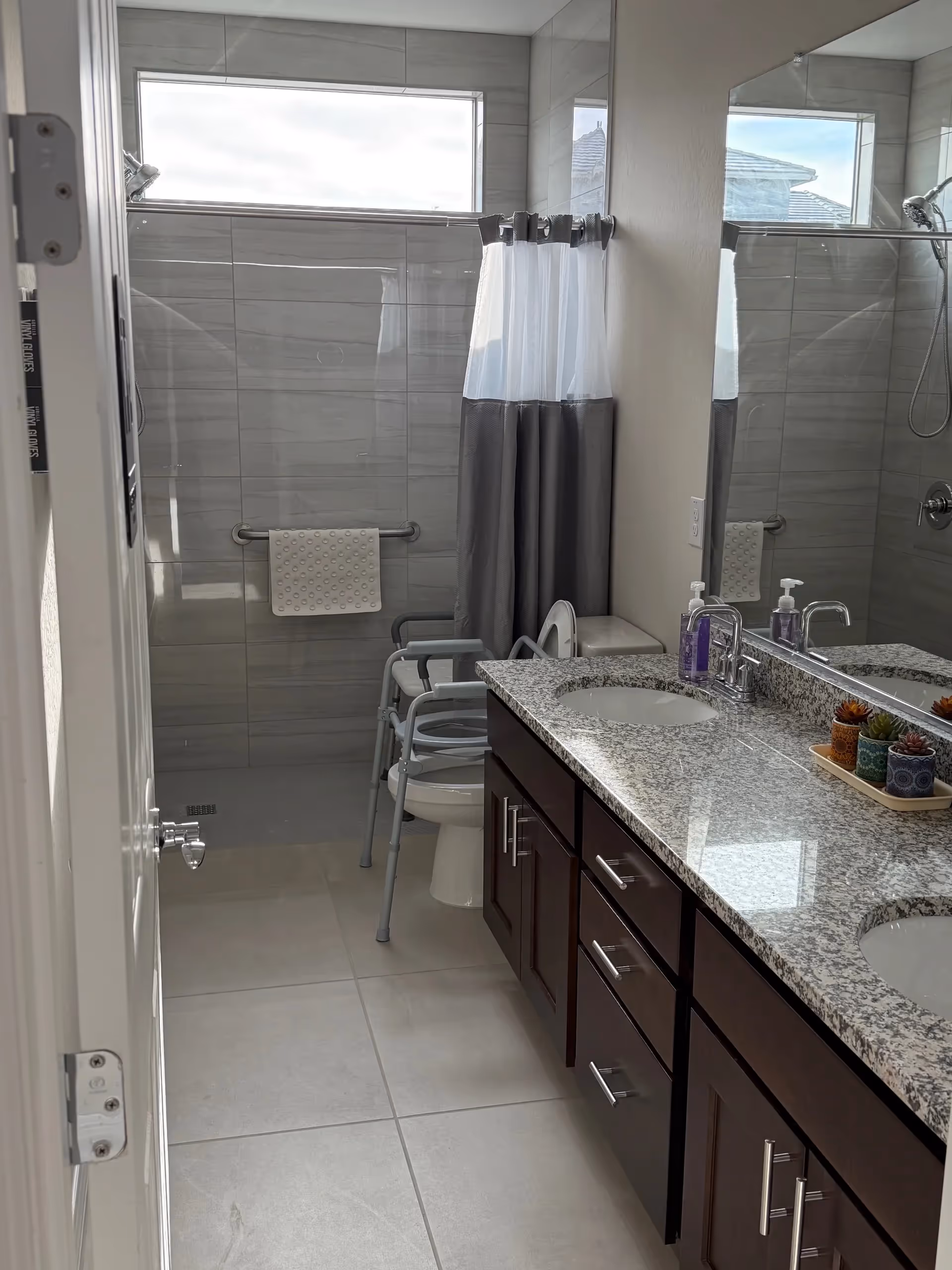 Modern bathroom with double sink vanity, granite countertop, walk-in shower, and accessible features.