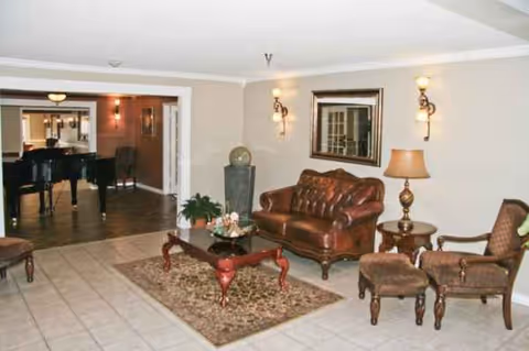 Spacious lobby seating area with leather furniture, coffee table, lamps, and a doorway to dining area.