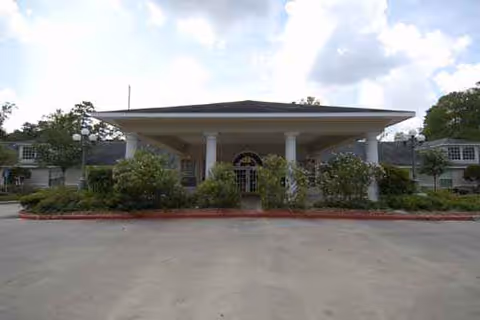 Front view of Ridgewood at the Woodlands entrance with columns and landscaped shrubbery.