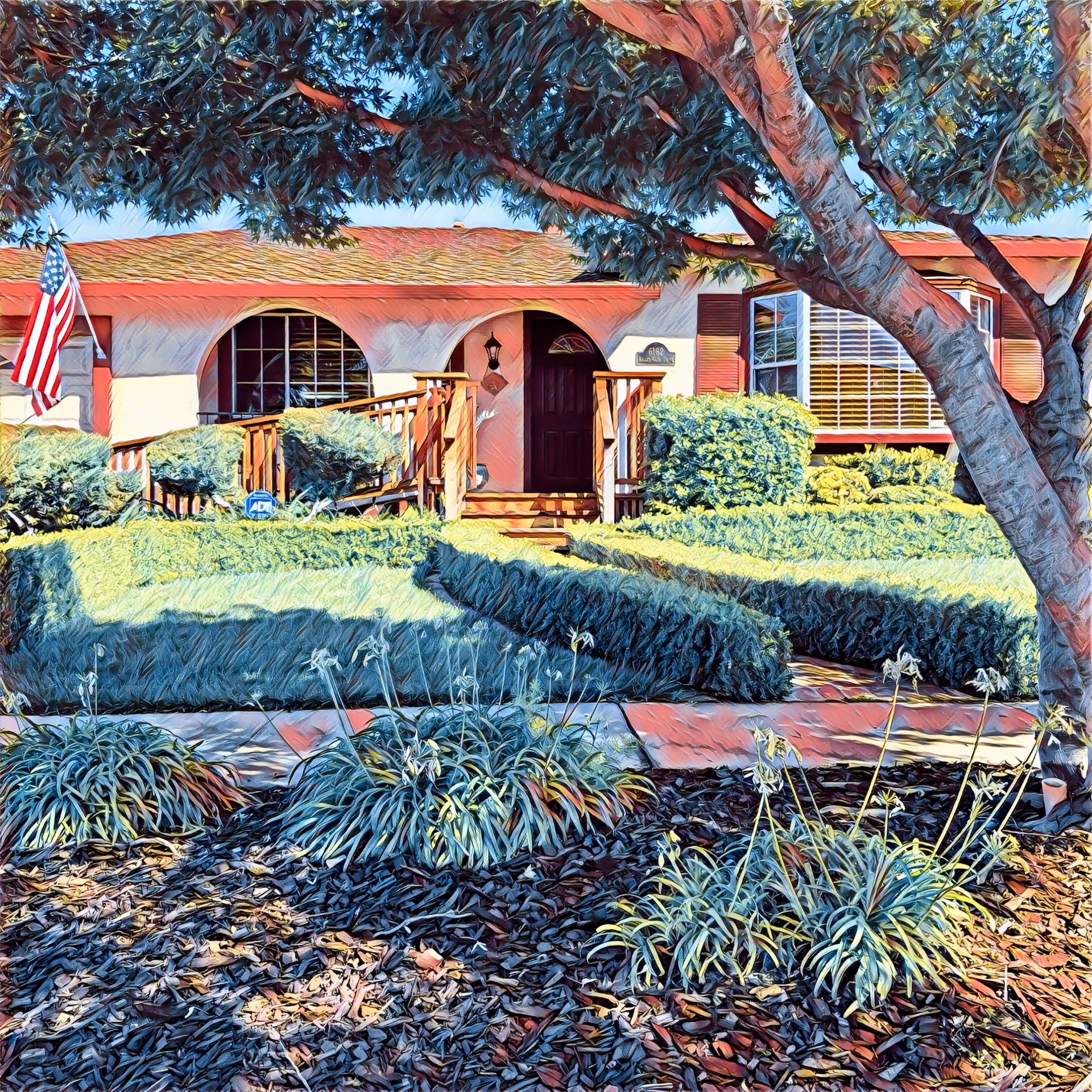 Front exterior of a single-story home with an arched porch, wooden steps and railing, neatly trimmed hedges, an American flag, and a large tree in the yard.