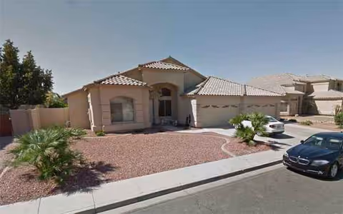Front exterior of Arrowhead Adult Care Home, a single-story house with gravel landscaping and parked cars.