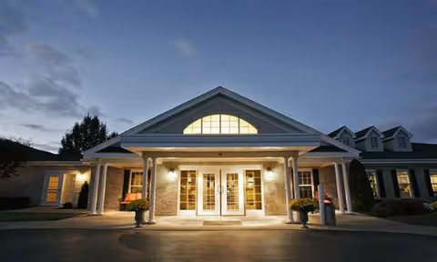 Front entrance of Tennyson Court senior living facility with lit doorway and columns.