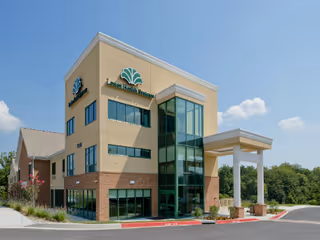 Modern three-story senior living facility exterior with glass entry and signage.