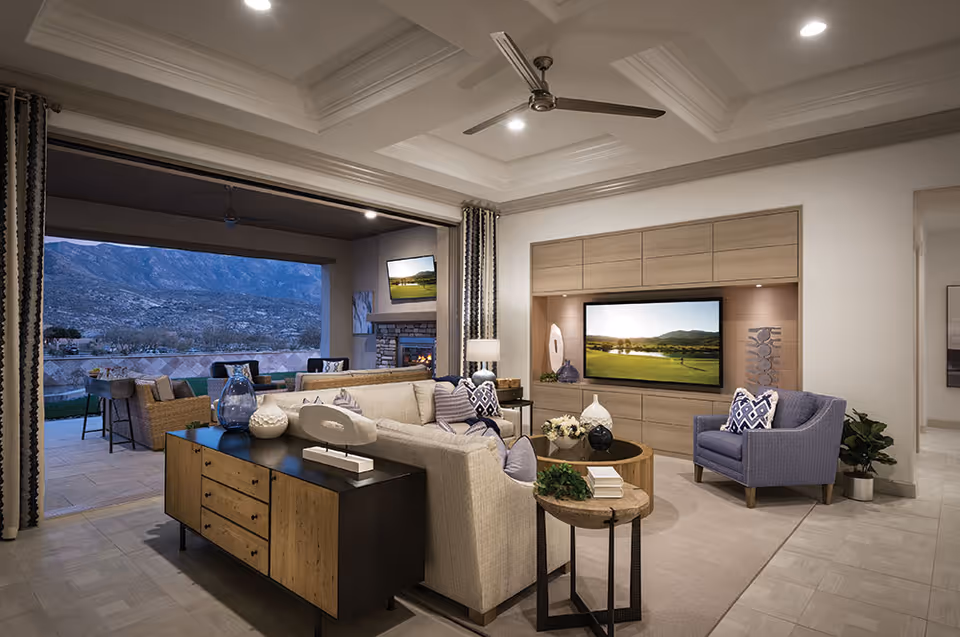 Contemporary living room with a sofa, armchairs, built-in TV, and an open wall leading to an outdoor patio with a mountain view.