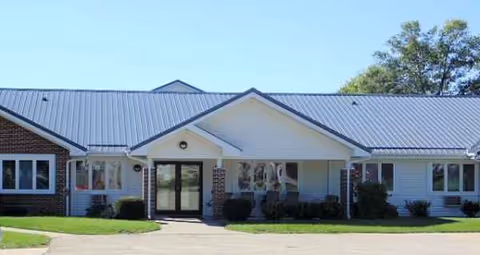 Exterior view of a single-story senior living facility with a central entrance and windows.