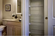 Bathroom with a vanity and mirror on the left and an open linen closet with wire shelves on the right.