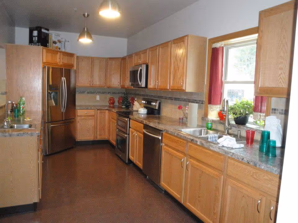 Spacious kitchen with wooden cabinets, stainless steel appliances, and a sink under a window.