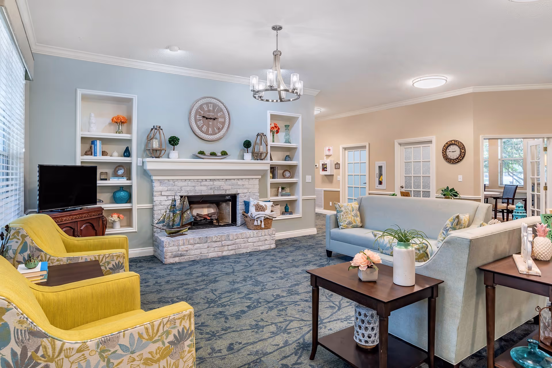Bright communal living area with a fireplace, shelves, and seating.