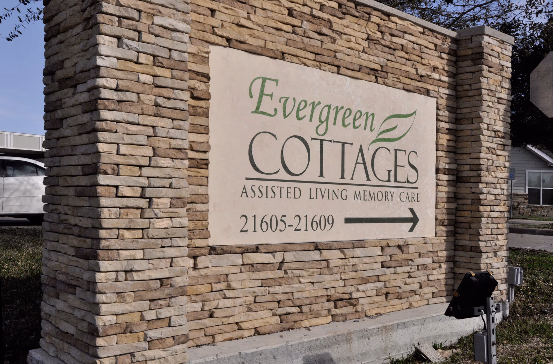 Stone entrance sign reading Evergreen Cottages Assisted Living Memory Care with arrow