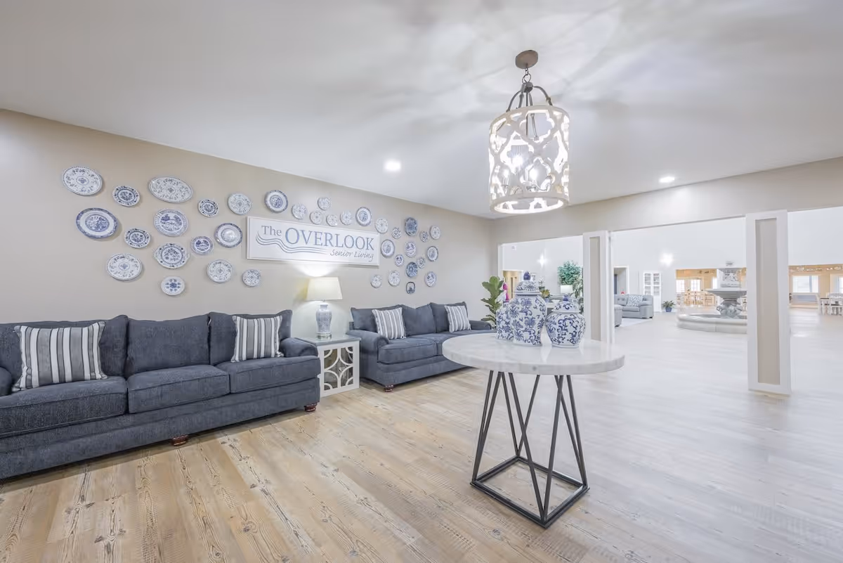 Spacious senior living lobby with blue sofas, decorative plates on the wall and a round table topped with blue-and-white vases.