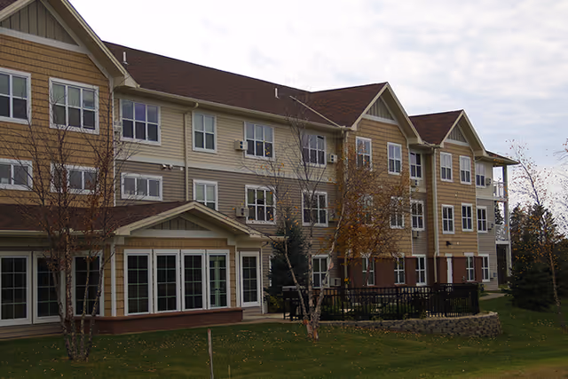 Exterior view of Ecumen Prairie Hill senior living building with beige siding and a lawn.