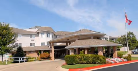 Exterior view of The Gardens at Arkanshire Senior Living entrance with porte-cochère and landscaping.
