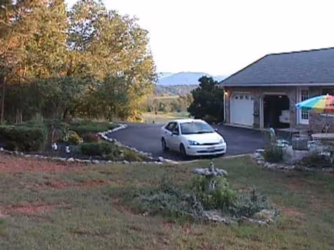 A car parked in a driveway in front of a single-story senior living facility with landscaping.