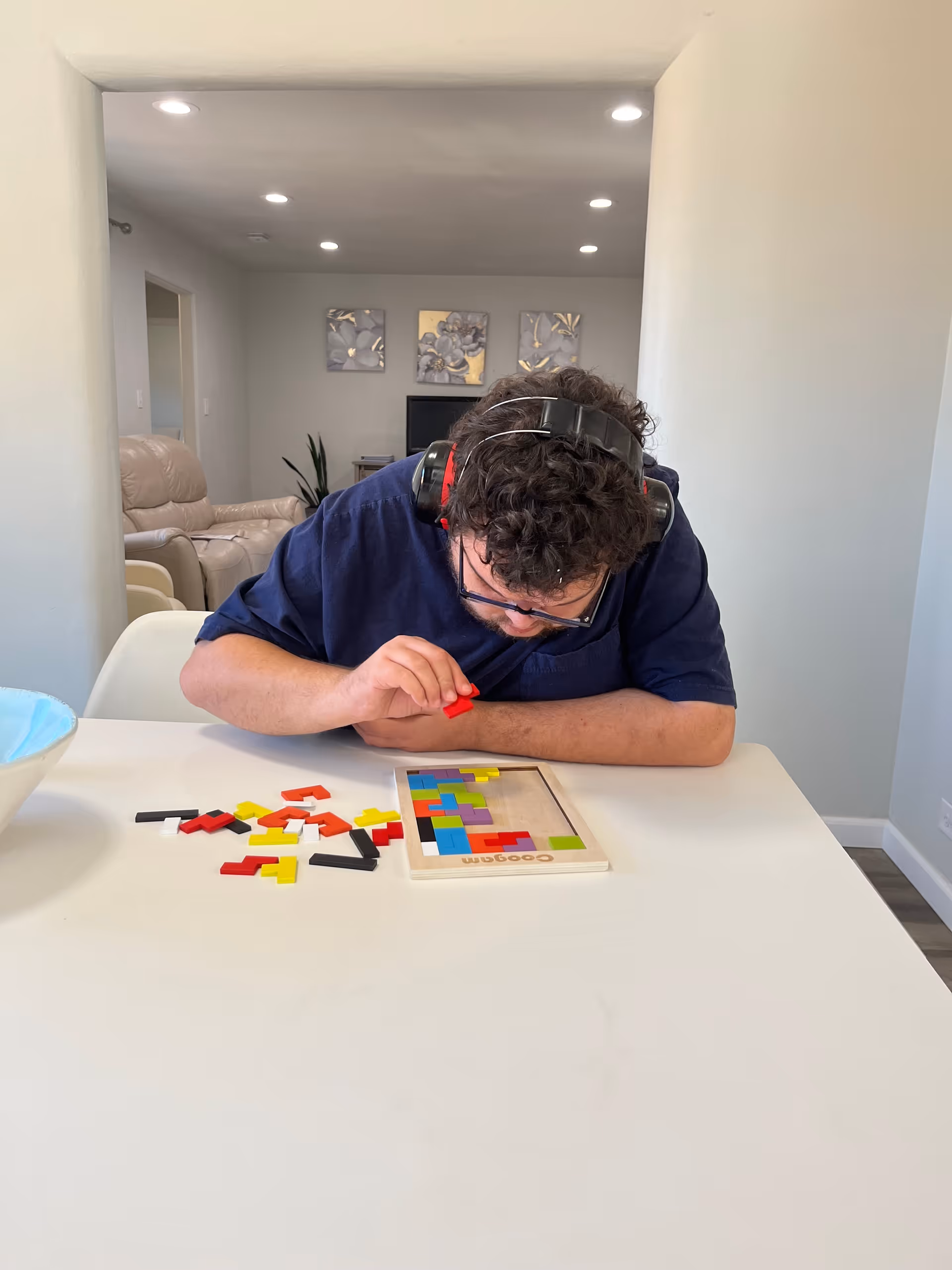 A person playing a game with colorful pieces on a table in a bright room.