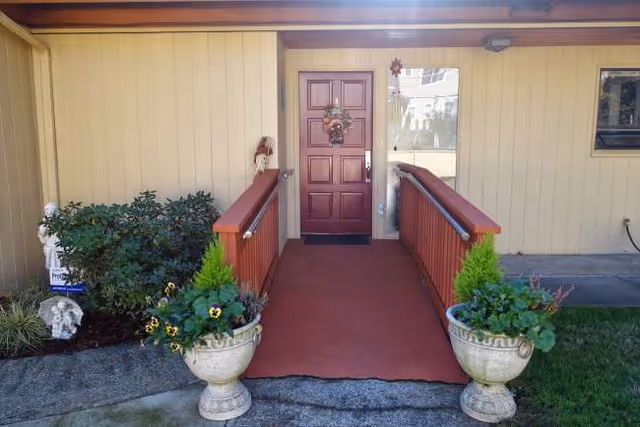 Front entrance of Harmony Care Adult Family Home with a red ramp, planters, and wreath.
