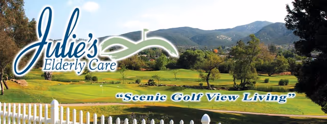 A scenic view of a golf course with green grass, trees, and mountains in the background, with a white picket fence in the foreground. The image includes the text 'Julie's Elderly Care' and the slogan 'Scenic Golf View Living'.