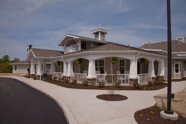 Front view of Rosecrest Residence, a white columned senior living building with curved driveway.