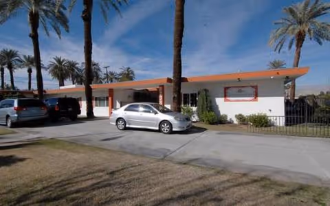 Desert Cove Boutique Assisted Living building exterior with palm trees and parked cars.