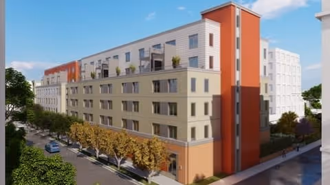 Exterior view of a multi-story senior living facility named Alate Old Town, featuring modern architecture with beige and orange accents, surrounded by trees and a street with parked cars.