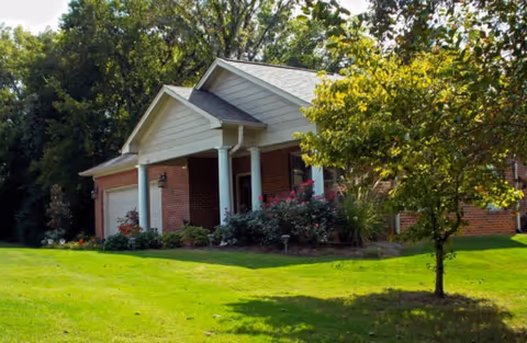 Front view of a brick retirement community with a covered entrance and landscaped grounds