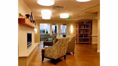 Cozy common living room with armchairs, a fireplace, bookshelf, and large pendant lights.