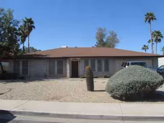 Exterior of Emerson Assisted Living Home, a single-story building with desert landscaping and palm trees.