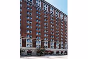 Tall red brick apartment building with many windows along a city street.