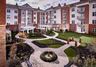 Landscaped central courtyard with walkways, seating and pergolas surrounded by a multi-story residential building.