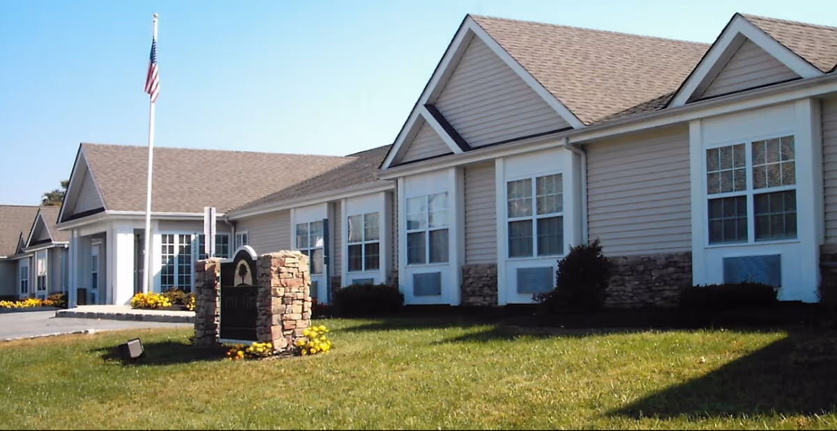 Exterior view of Merion Gardens Assisted Living building with flagpole and lawn.