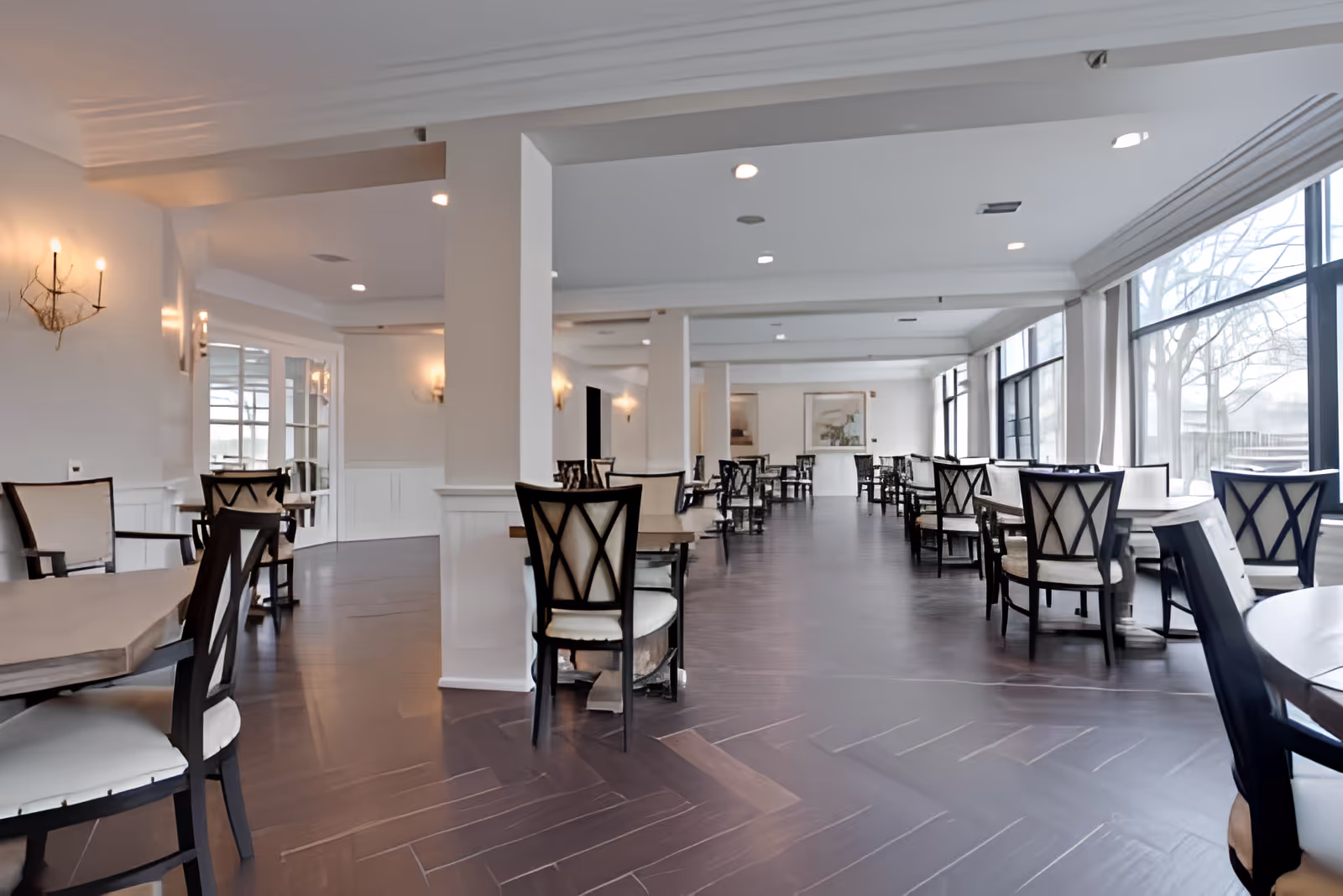 Bright, spacious dining room with multiple tables and chairs arranged along large windows.