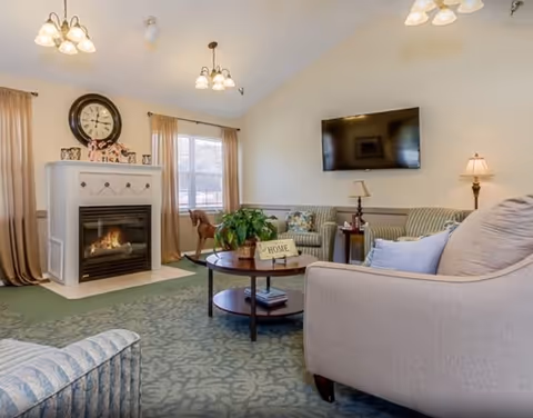 Cozy common room with sofas, a coffee table, fireplace, and wall-mounted TV.
