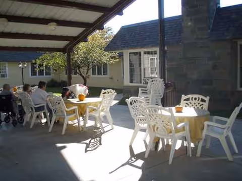 Outdoor covered patio with white plastic chairs around yellow-cloth tables