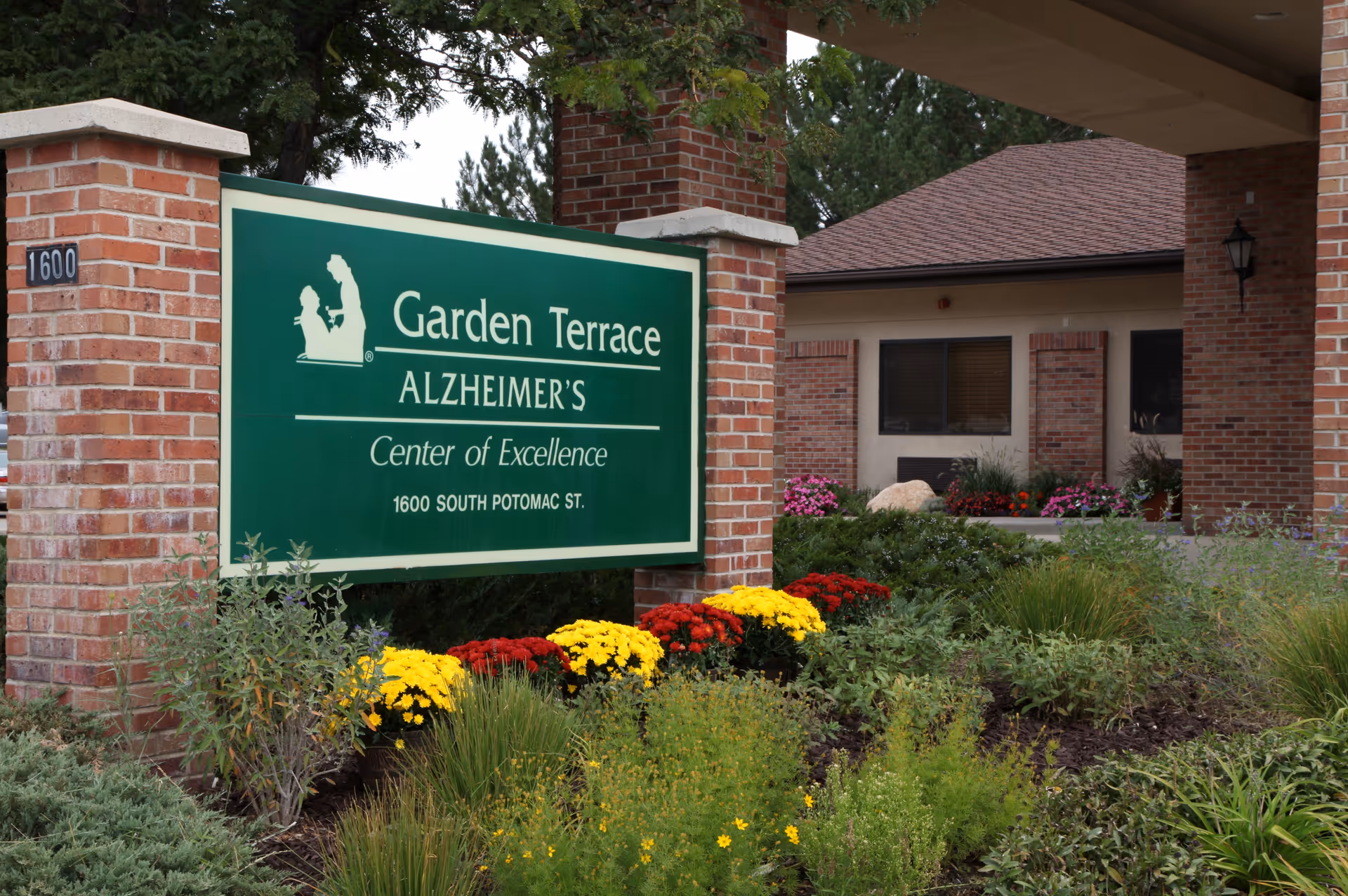 Entrance sign for Garden Terrace Alzheimer's Center of Excellence in front of a brick building with flowers and landscaping.