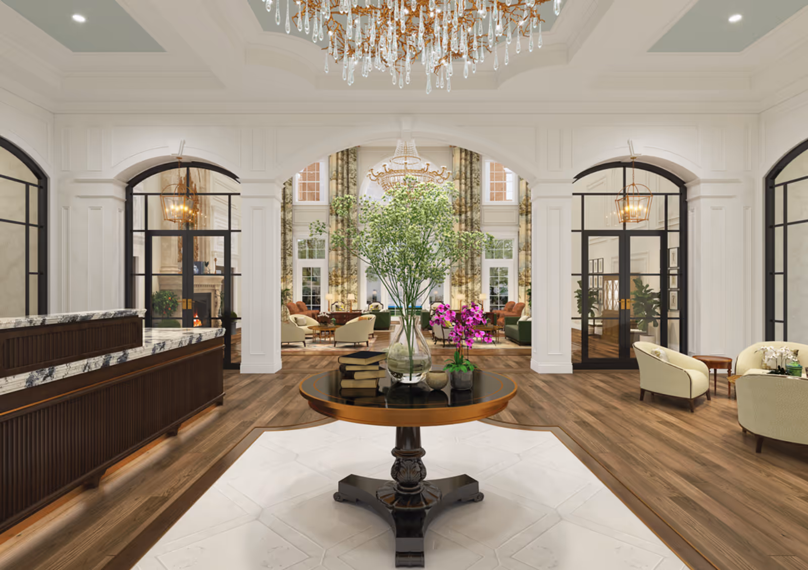 Elegant senior living facility lobby with a round wooden table in the center holding a vase with green branches, a small pot with purple flowers, and a stack of books. The room features white walls with decorative molding, large arched doorways with black-framed glass doors, a marble-topped reception desk on the left, and comfortable seating areas with armchairs and sofas in the background. A large crystal chandelier hangs from the ceiling.