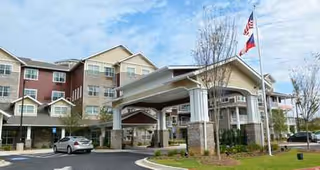 Exterior view of Ashwood Meadows Gracious Retirement Living entrance with porte-cochere and flag.