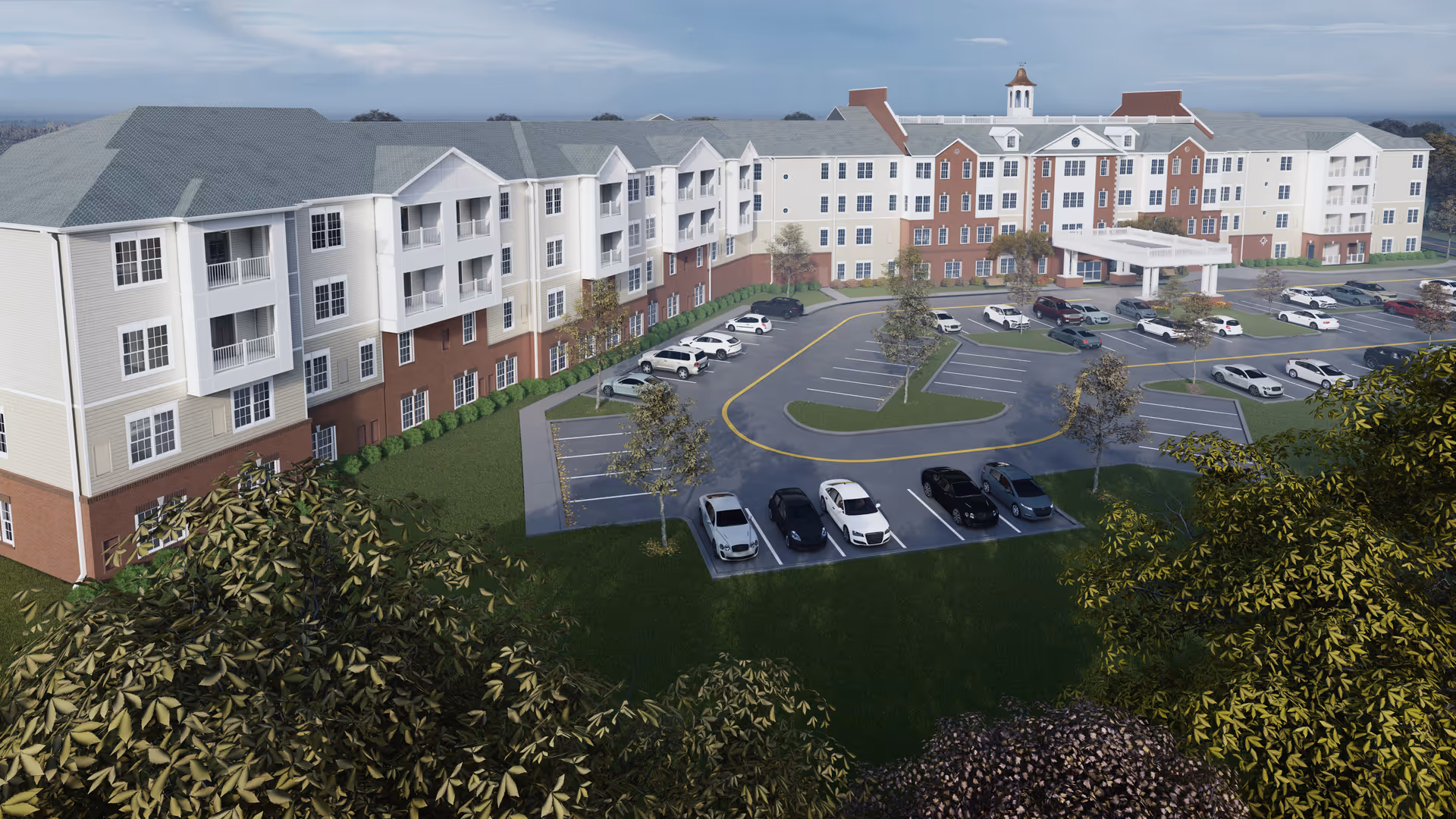 Aerial view of a multi-story senior living building with a circular driveway, parking lot, and surrounding landscaping.