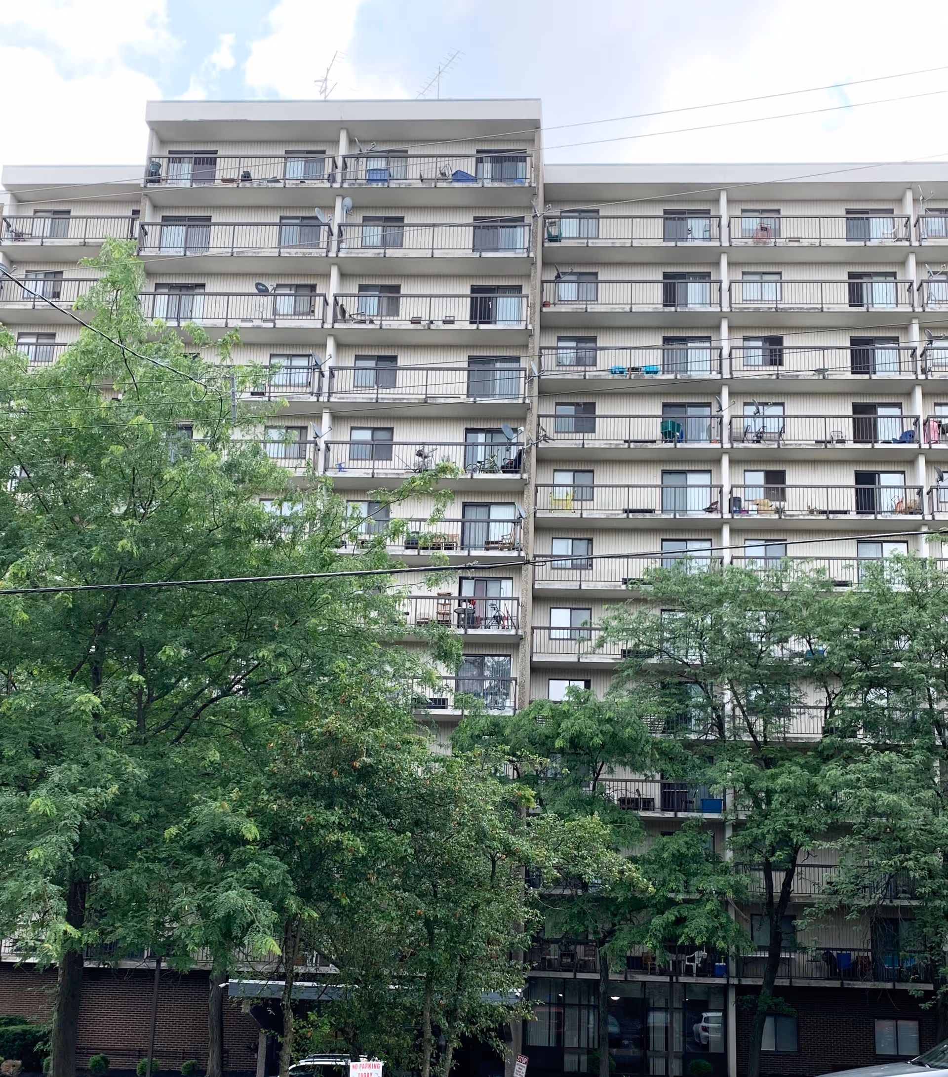 Exterior view of a multi-story senior living facility named Senior Chateau with balconies on each floor and trees in the foreground.