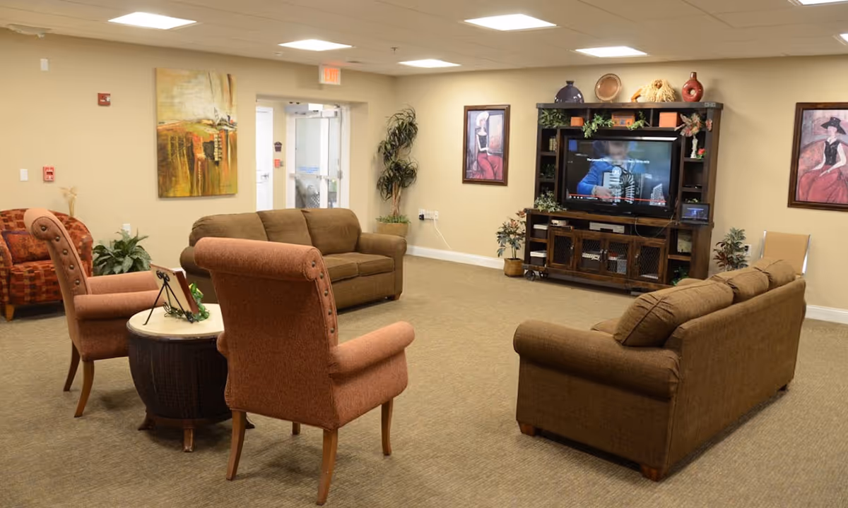 Common living room lounge with sofas, armchairs, a coffee table, and a TV entertainment center.